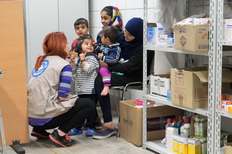 Una trabajadora de la organización humanitaria Médicos del Mundo atiende a una familia refugiada en una clínica móvil en Grecia